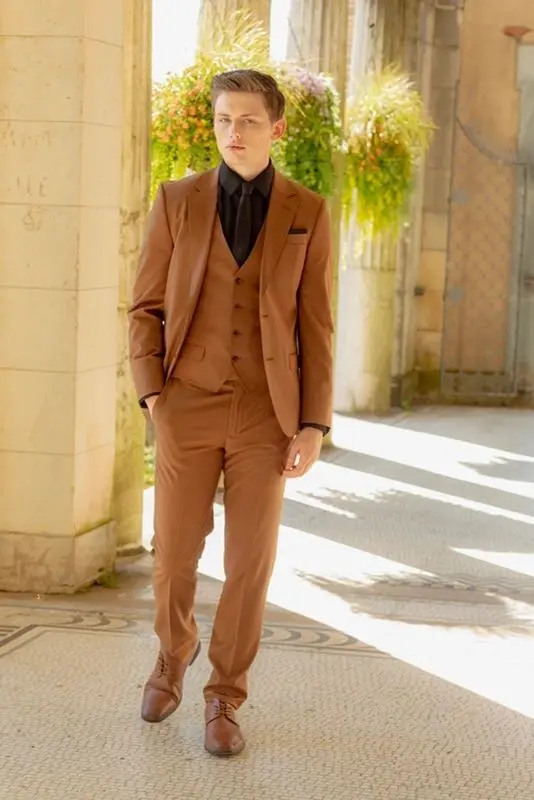 A man in brown suit standing on the sidewalk.