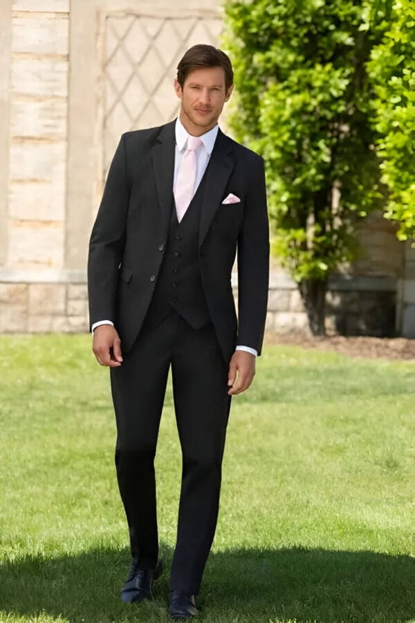 A man in a suit standing on the grass.